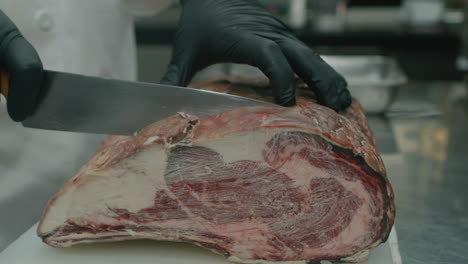de cerca en la mano del chef cortando enorme carne de res seca australiana con un cuchillo de cocina