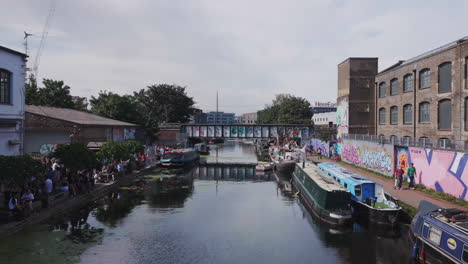 the regent's canal in hackney wick in london, with boats and people enjoying themselves