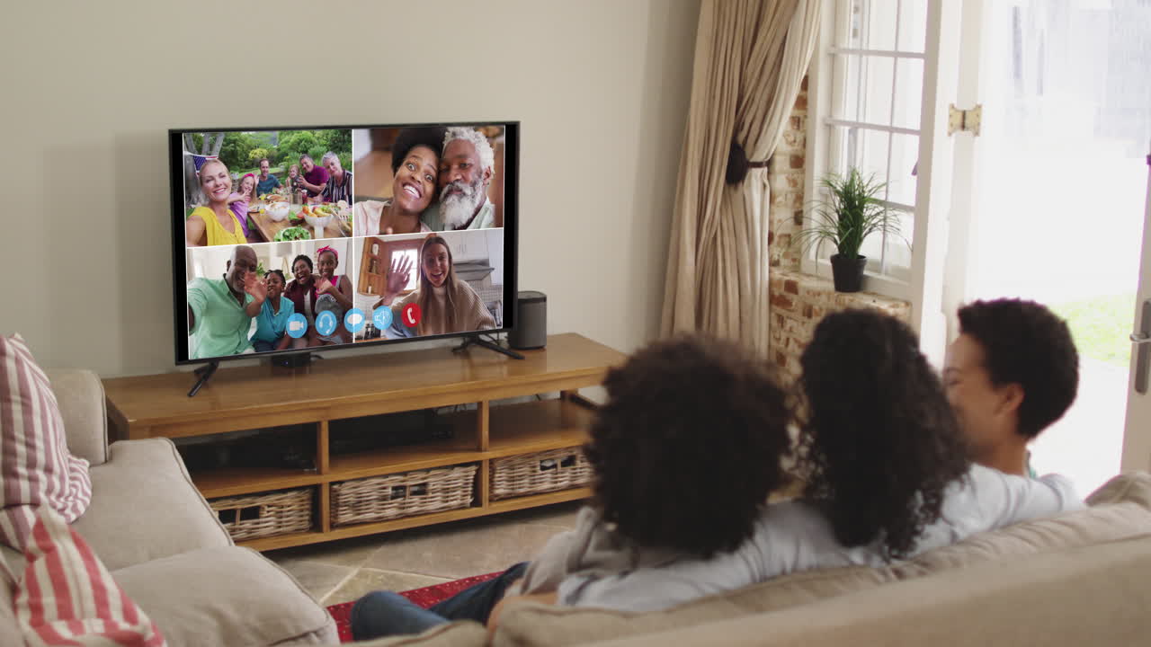 Famiglia afroamericana che fa una videochiamata in TV mentre è seduta sul divano a casa