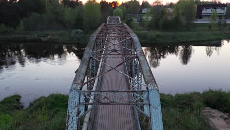 puente peatonal sobre el río gauja al atardecer, sobrevuelo en ángulo bajo