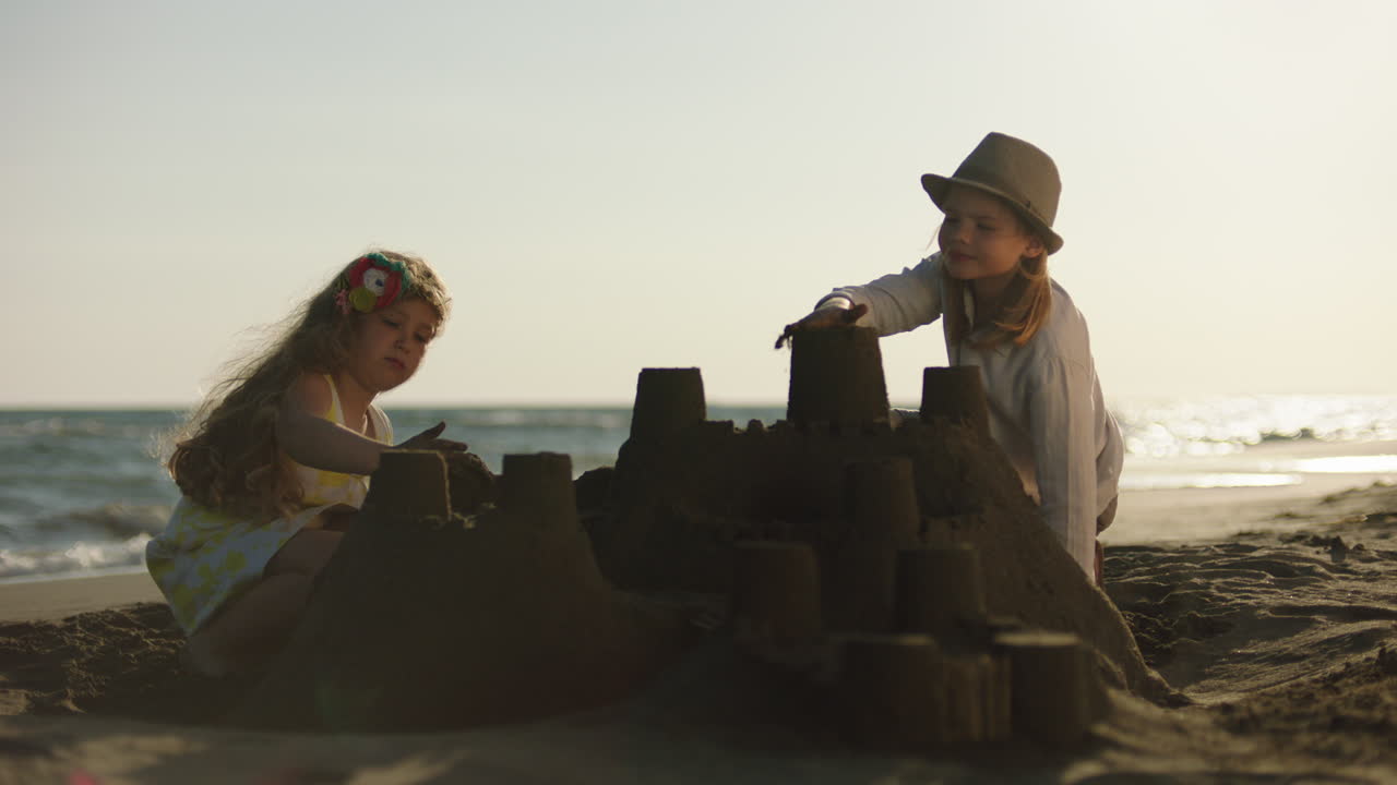 дети строят песчаный замок на пляже.