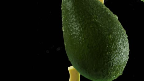aguacate con rebanadas y salpicaduras cayendo sobre un fondo negro
