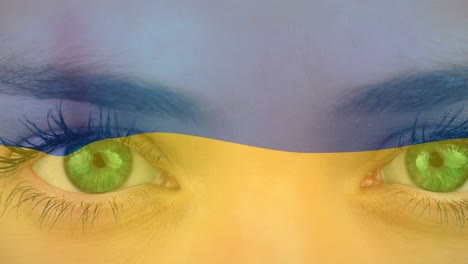 animation of flag of ukraine waving over open eyes of caucasisan woman