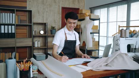 asian young male fashion designer sketching out new fashion collection. small business starts up designer, clothing shop owner, freelancer work at home. dressmakers working on clothes creation.