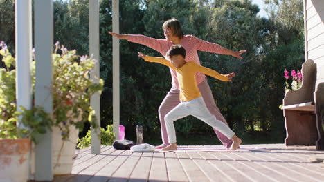 Abuela-Birracial-Y-Nieto-Haciendo-Yoga-Y-Estirándose-En-La-Terraza-De-Casa,-Cámara-Lenta