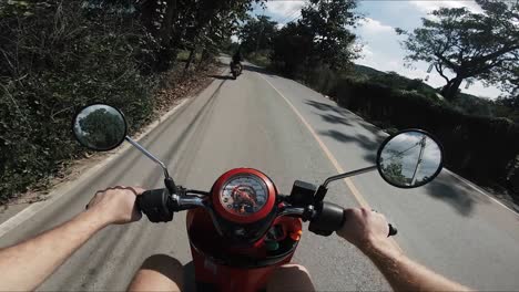 toma pov de un hombre conduciendo un ciclomotor por una carretera rural en tailandia