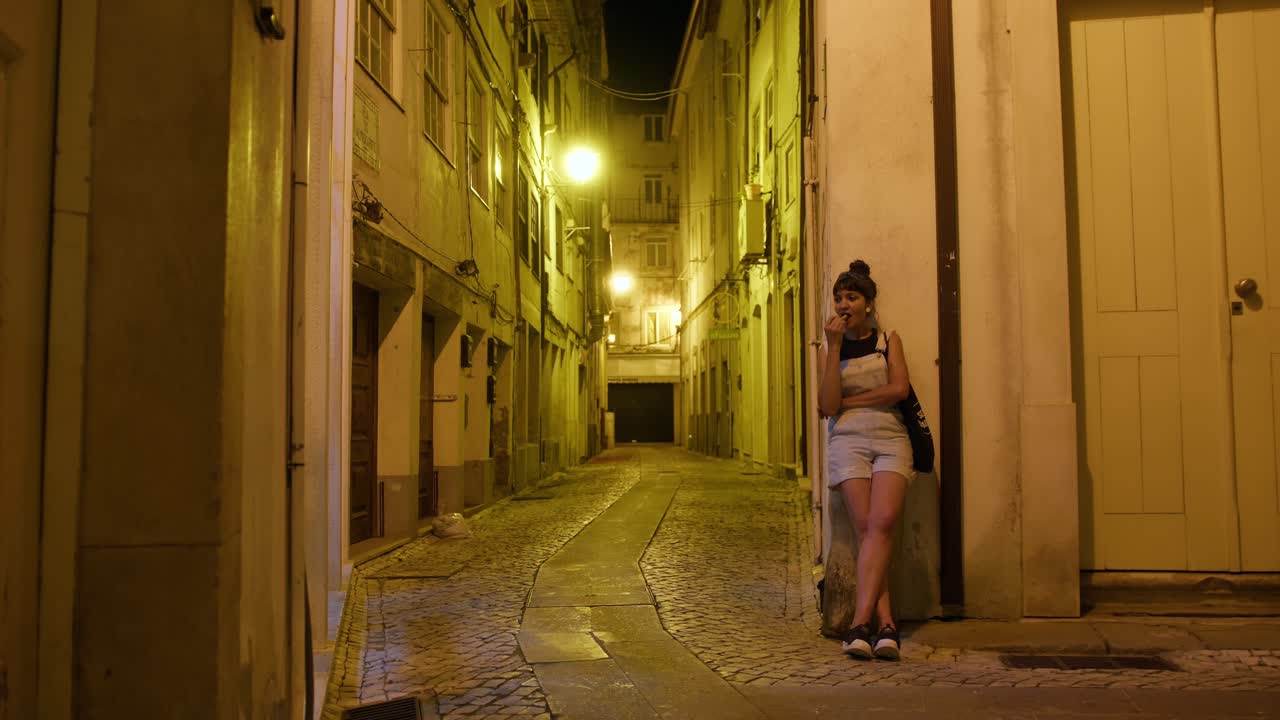 Slow motion of a Latin woman reflecting deeply at night in the streets of Coimbra, Portugal