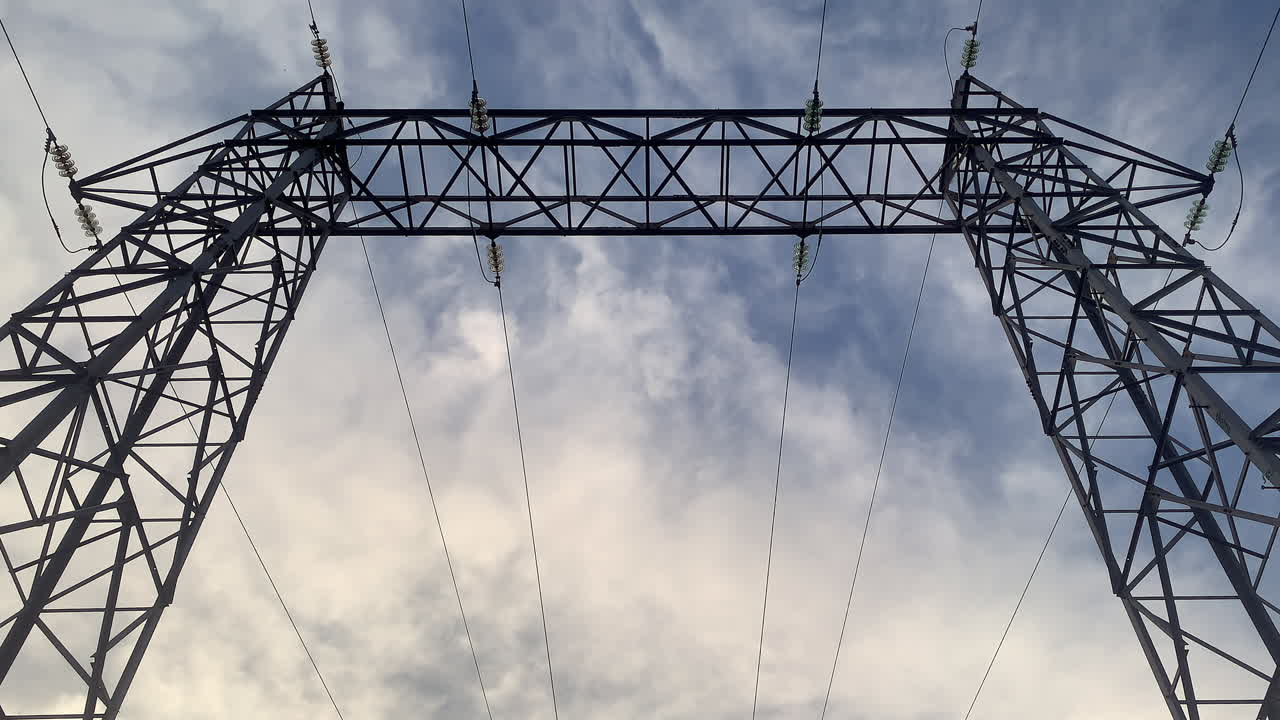 Static timelapse of high-voltage gantry as clouds race past, ideal energy and infrastructure opener