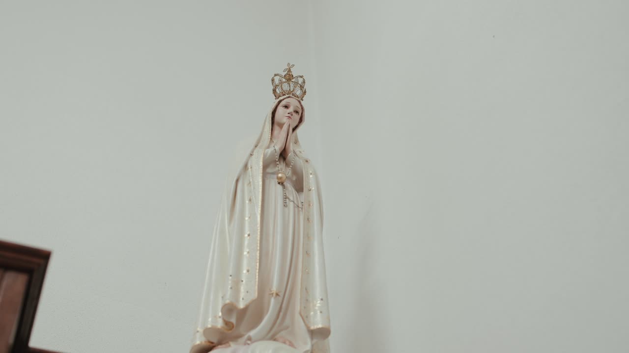 Primo piano della statua della Vergine Maria con una corona e le mani giunte in preghiera