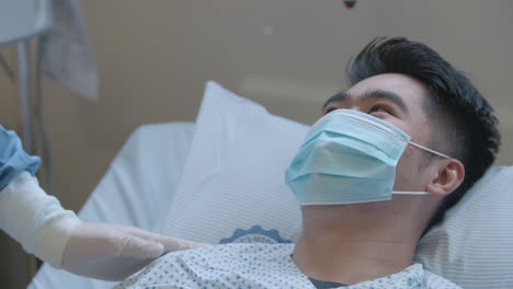 young male patient in chemotherapy talking to the doctor while nodding and wearing a face mask