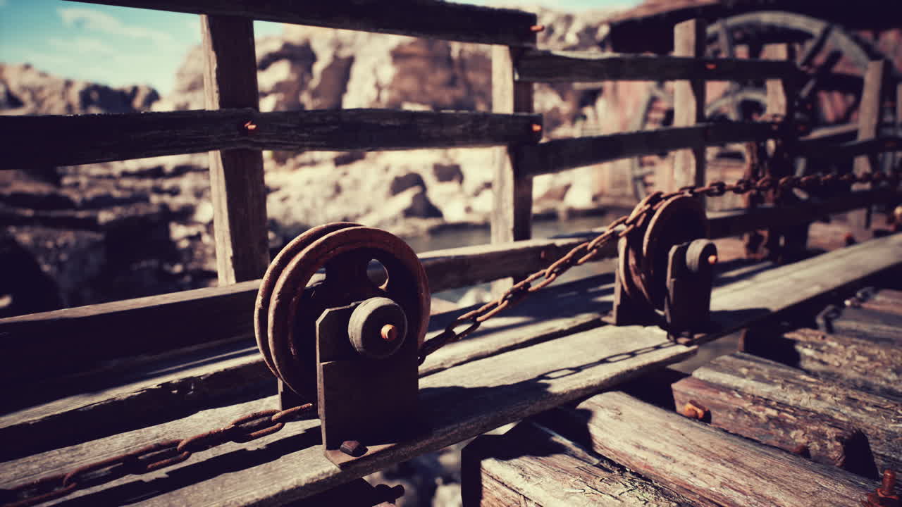 Old wooden bridge with pulleys and chains overlooking a rocky landscape