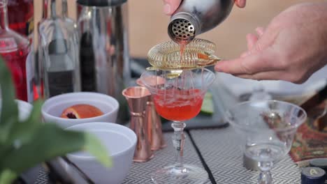 Outdoor-bar-with-a-cocktail-being-poured-into-a-crystal-glass-on-a-spring-themed-table