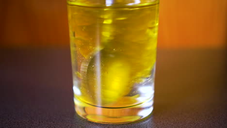 close-up of oil and water layered in a glass being stirred with a spoon