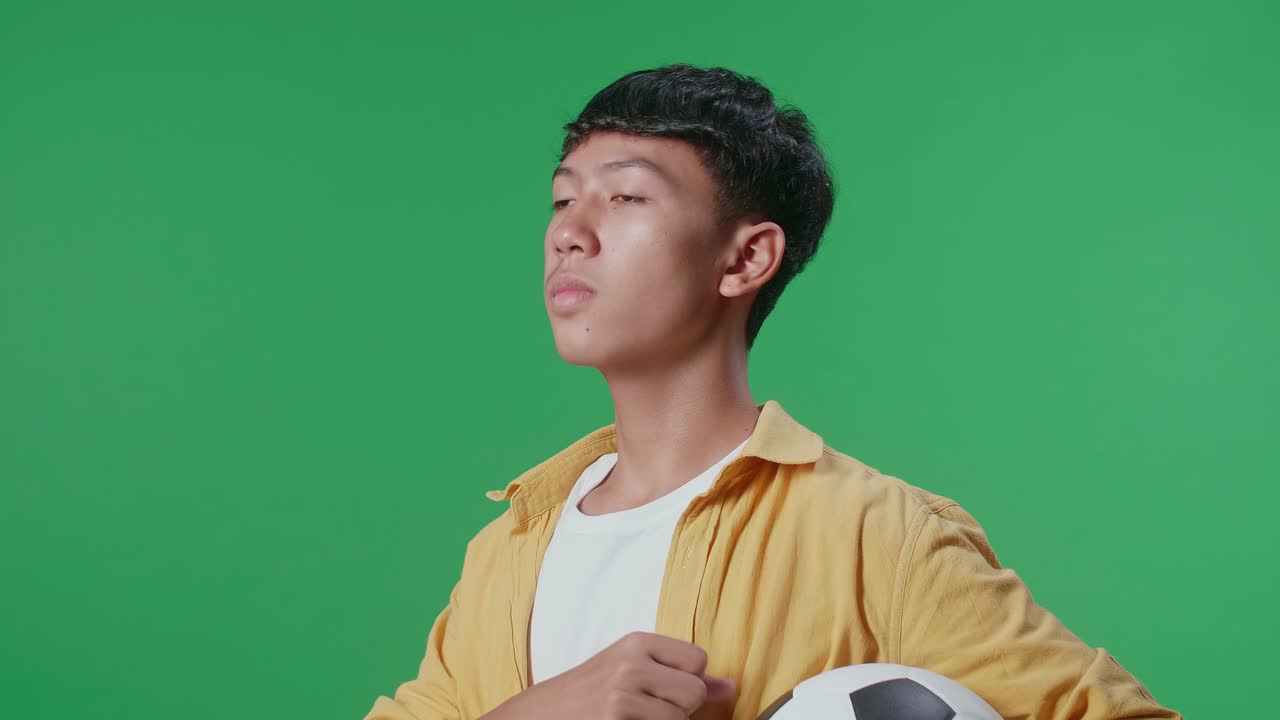 초록색 화면에서 축구공을 들고 있는 십대
