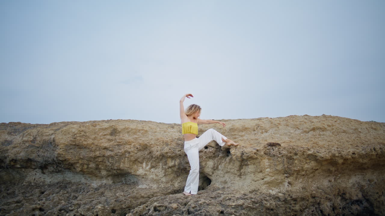 mujer bailarina suave moviendo el cuerpo flexible levantando la pierna en la roca pedregosa. niña bailando
