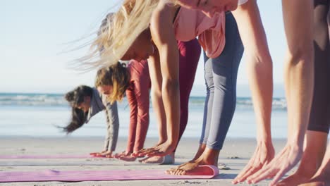 group of diverse female friends practicing yoga at the beach
