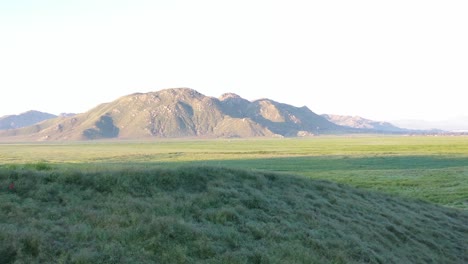 slow pan drone flight reveals a valley of green grass and mountains