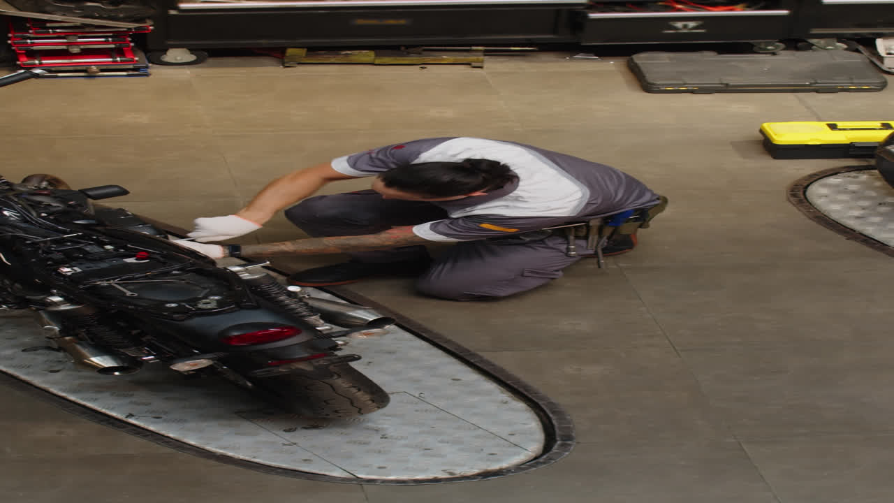 High Angle of Mechanic Examining Wheels of Motorbike