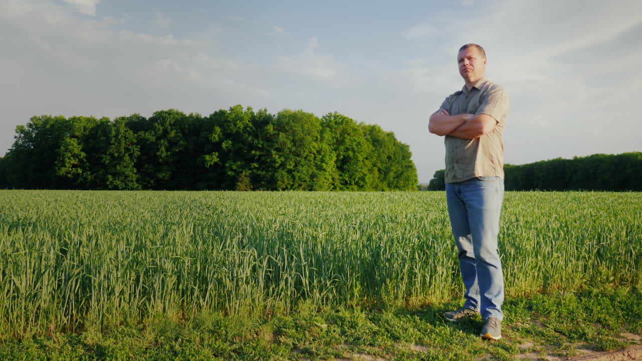 중년의 자신감 있는 농부가 자신의 밭을 살펴보고 있습니다.