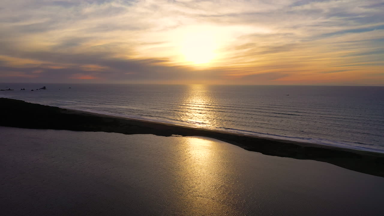오레곤의 담수호인 플로라스 호수와 오레곤의 태평양에서 반짝이는 물의 고정된 드론 영상은 얇은 땅으로만 나누어져 있습니다.
