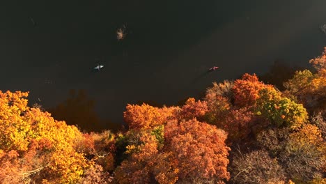 top down aerial of people in canoe and kayak on calm dark water lake