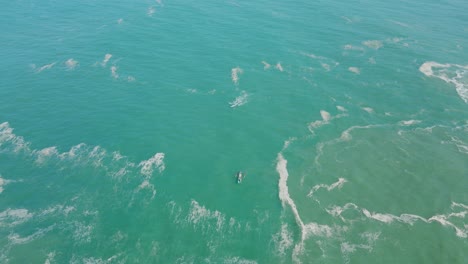 high bird's eye view over an azure blue ocean with a small traditional fishing boat