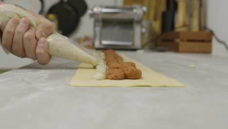 el chef agrega salsa de champiñones a la masa de lasaña