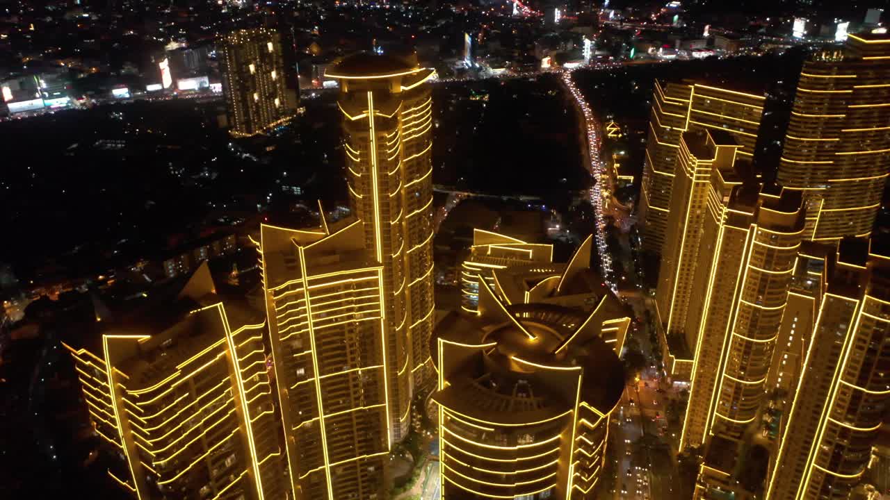 Aerial footage of Rockwell Center skyscrapers in Makati, Metro Manila, glowing with lights at night and surrounded by the vibrant energy of the city and its skyline.