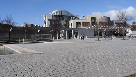 couple walk across the courtyard to the front of the scottish parliament building