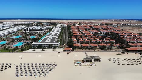 sombrillas de playa bikini con villas y piscinas en segundo plano.