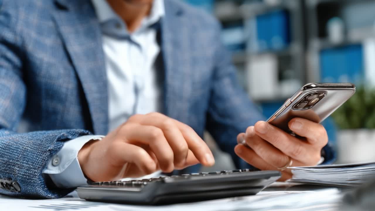Profissional Engajado em Cálculo Financeiro com Smartphone em Uma Mão e Calculadora na Outra, Demonstrando Práticas de Negócios Modernas e Integração Tecnológica