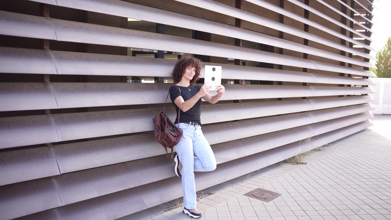 Una giovane donna con un tablet di fronte a uno sfondo architettonico contemporaneo