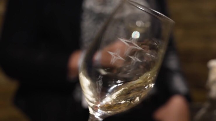 Primo piano di un bicchiere di vino bianco fatto roteare per rilasciare i suoi composti aromatici.