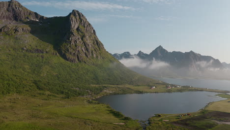 Drone slowly flying above Lofoten mountain and misty coastal valley in morning light