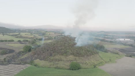 A-mild-forest-fire-on-a-hill-on-a-cloudy-day,-smoke-poised-to-erupt-into-flames