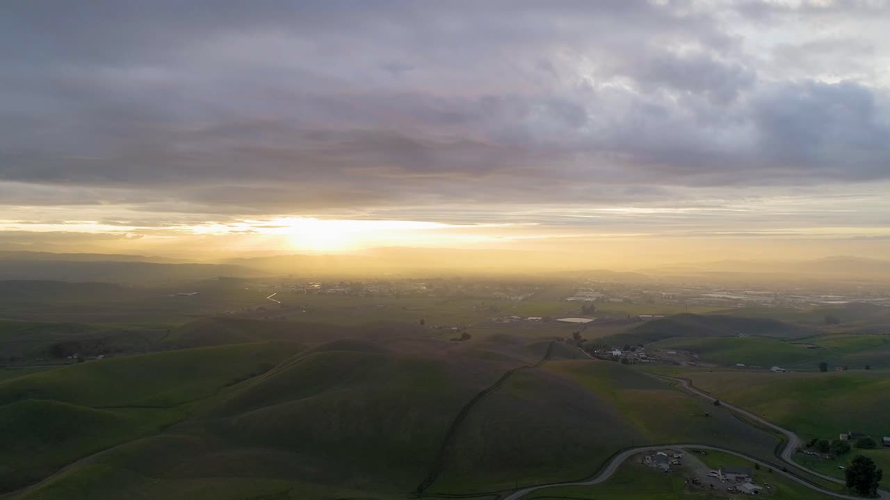 Forward Dolly of Moody Clouds at Sunset and Winding Road Passing Through Rolling Hills