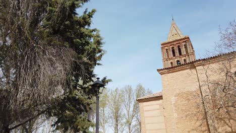 trees blowing in the wind by a spanish church