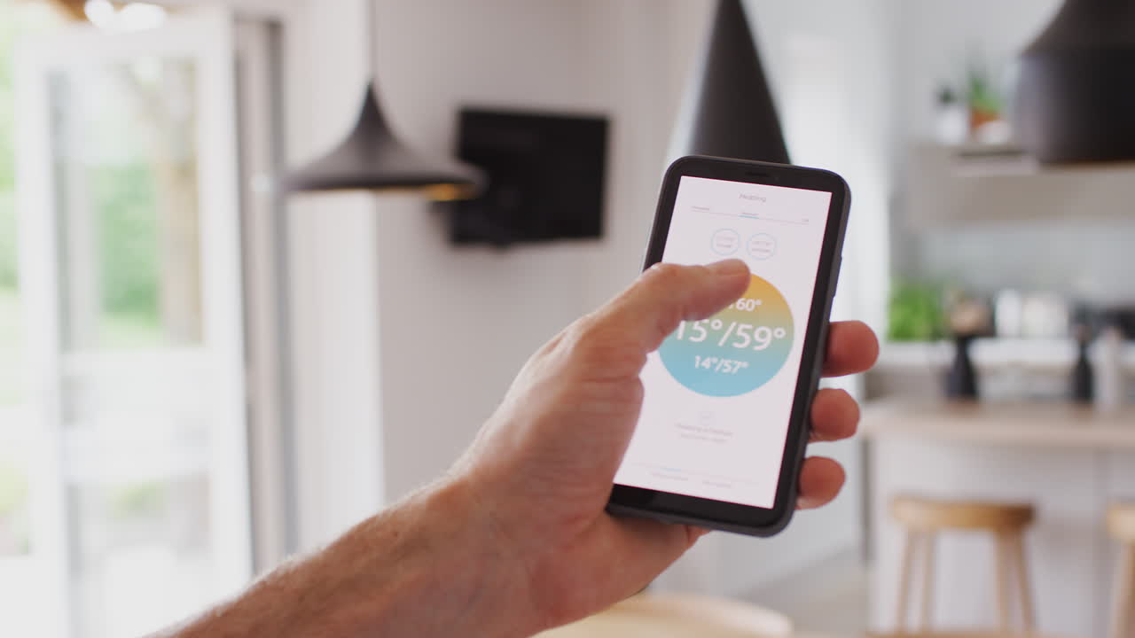 primer plano de un hombre que utiliza una aplicación en su teléfono inteligente para controlar la temperatura de la calefacción central en la casa