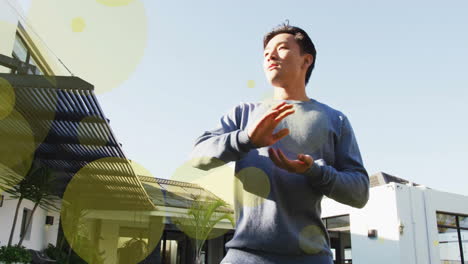 Animation-of-spots-of-light-over-biracial-man-exercising-in-garden-at-home