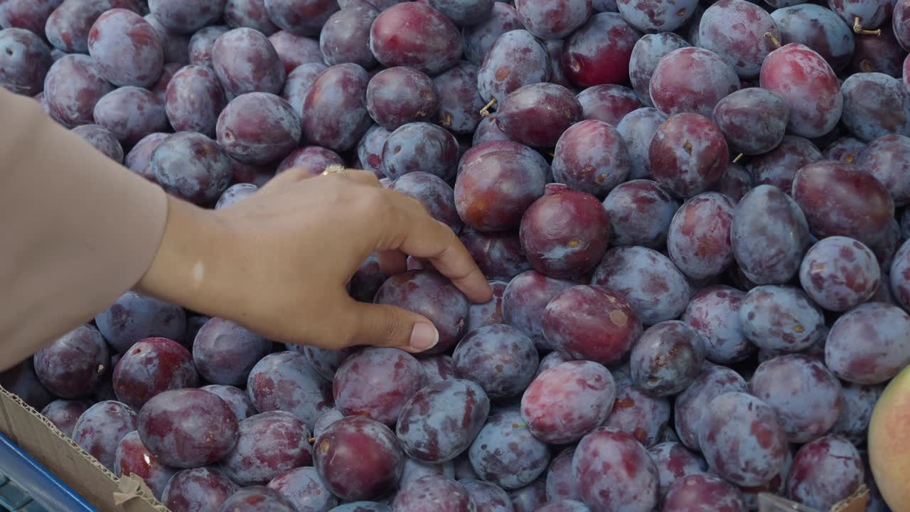 Vælger blommer på et marked