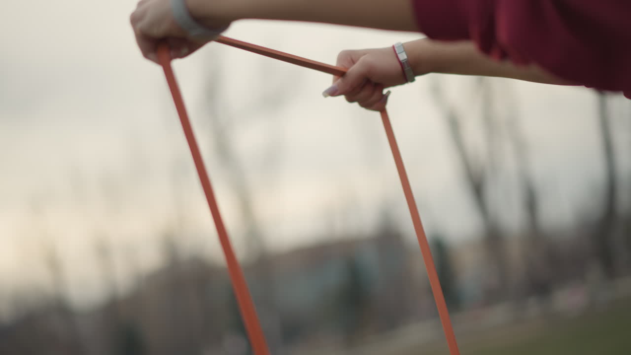 Outdoor Resistance Training Session, Therapeutic Wrist Resistance Workout Performed Outside With Focus, Caucasian Woman Engaged In Rehabilitative Wrist Exercises Using Resistance Bands Outdoors