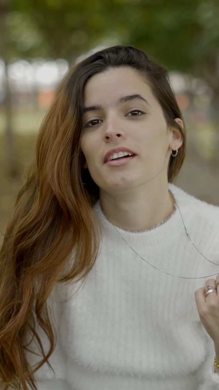 Portrait of a young woman in a white sweater outdoors