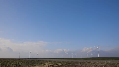 onshore horizontal axis wind farm turbine in green field at clear blue sky - wide angle shot