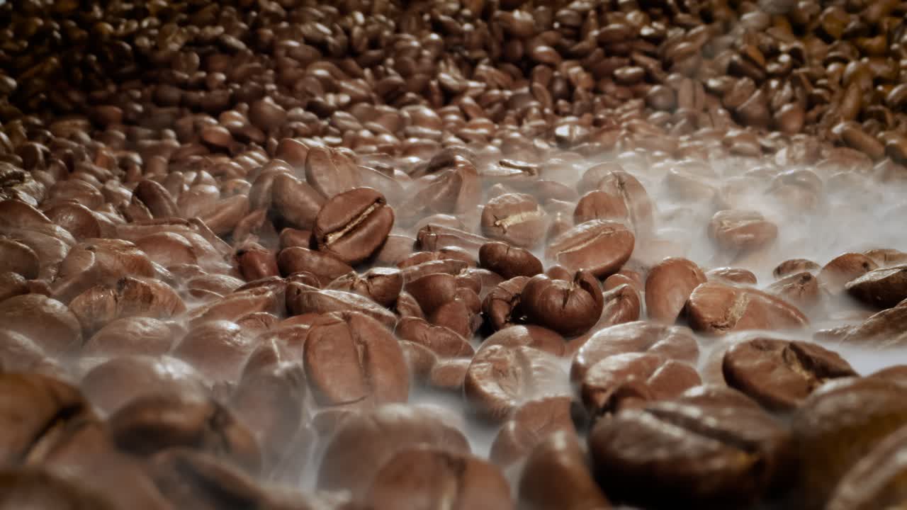 Close up of seeds of coffee. Fragrant coffee beans are roasted smoke comes from coffee beans.