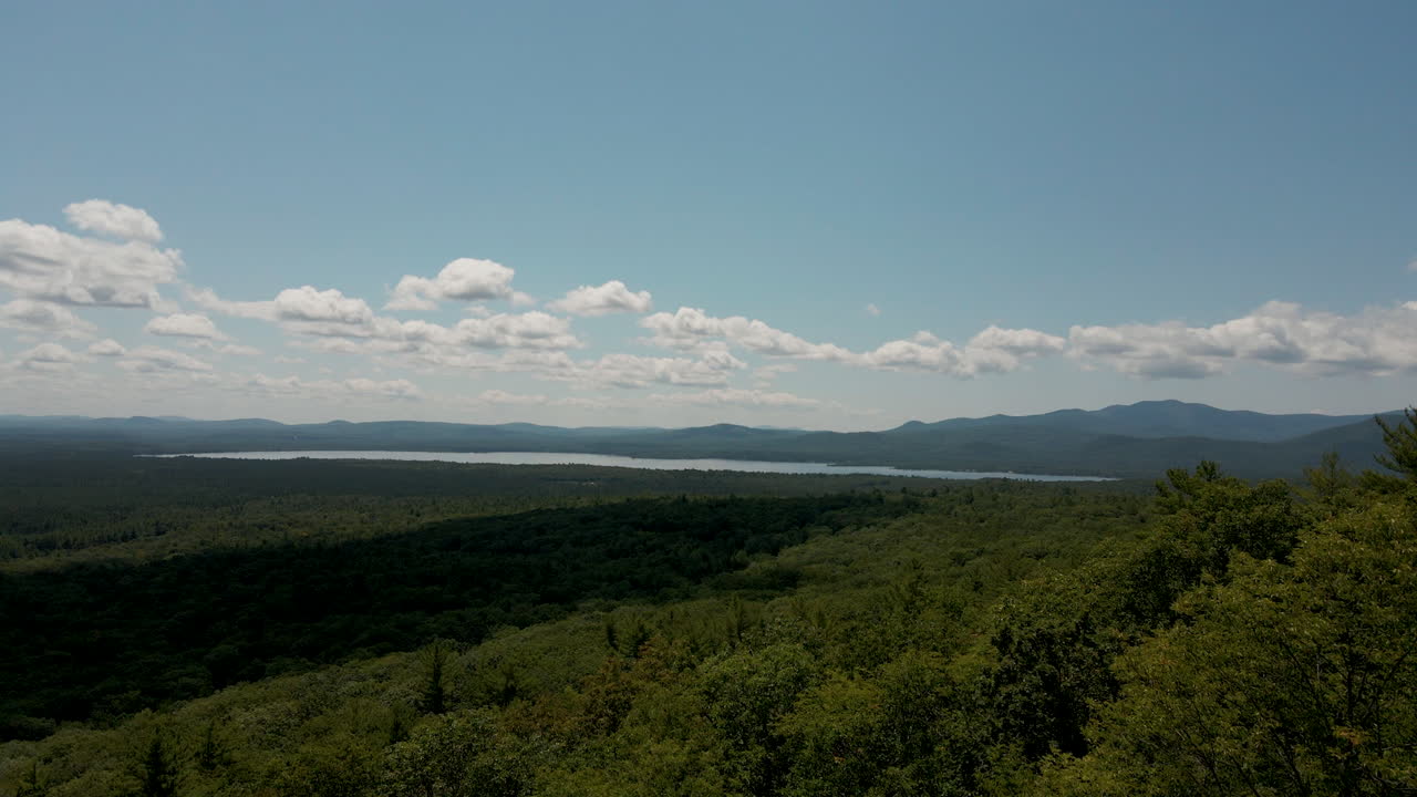 cumbre de la montaña despegue aéreo empujando a través de los árboles revelando el lago