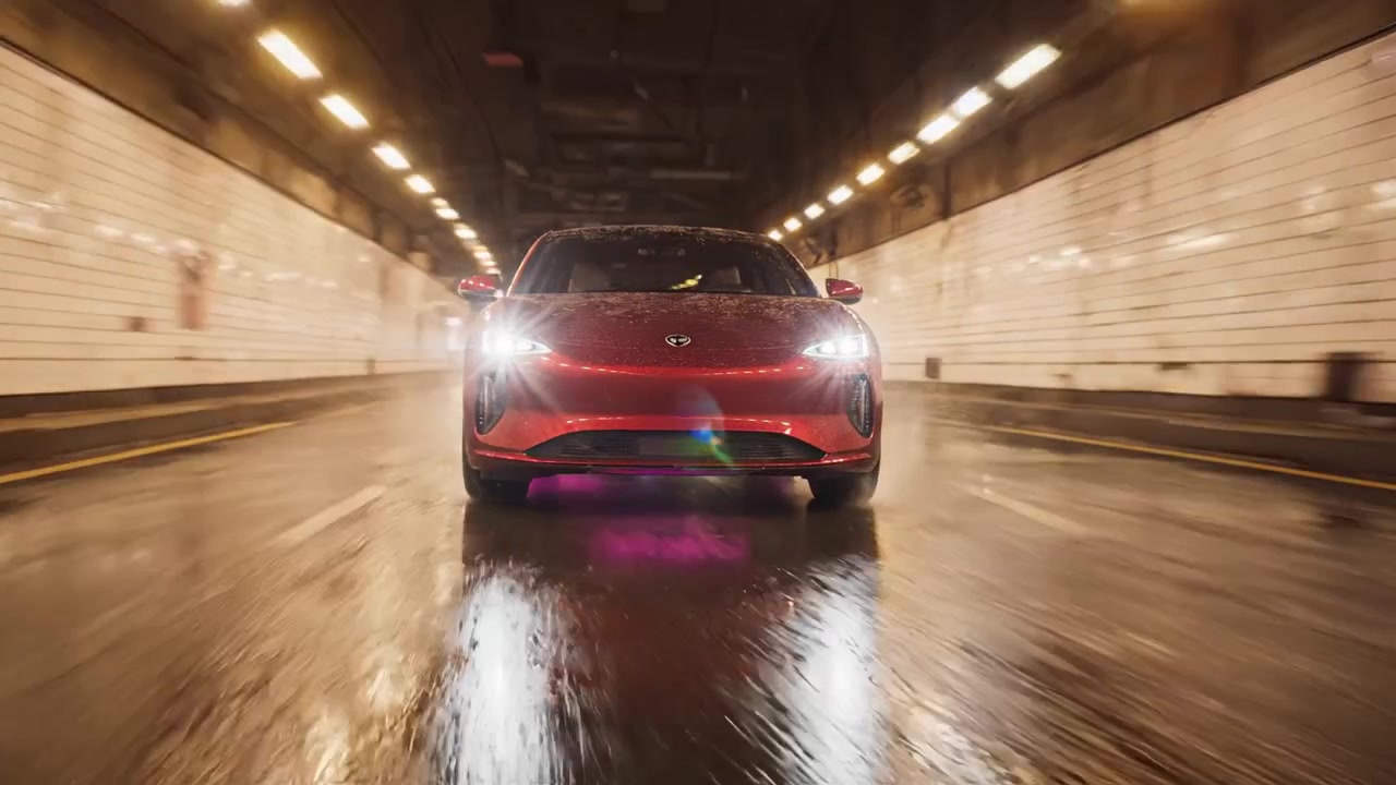 En elegant rød elbil suser gennem en våd tunnel, der fremviser sit stilfulde design og levende belysning, og legemliggør futuristisk bilteknologi i bevægelse