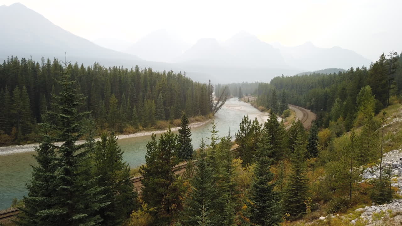 tren de carga en el ferrocarril pacífico canadiense en la curva de morant en alberta, canadá con vista al río bow desde la avenida del valle bow - lapso de tiempo
