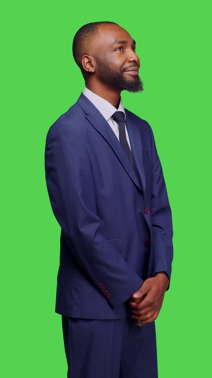 Video verticale: visuale laterale di un uomo d'affari sicuro di sé in piedi in uno studio con greenscreen