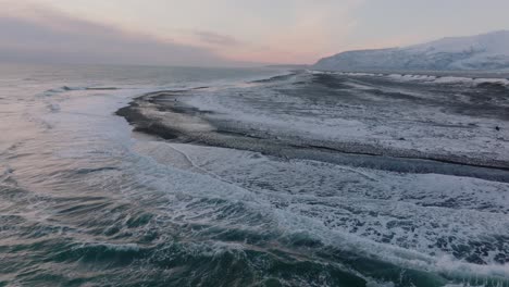 Luftaufnahme-Der-Meereswellen,-Die-Bei-Sonnenuntergang-Auf-Den-Schneebedeckten-Diamond-Beach-Krachen