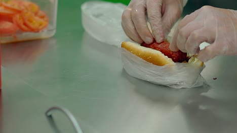 cu slow motion cook prepares a hot dog with cheese puts the fried sausage into it